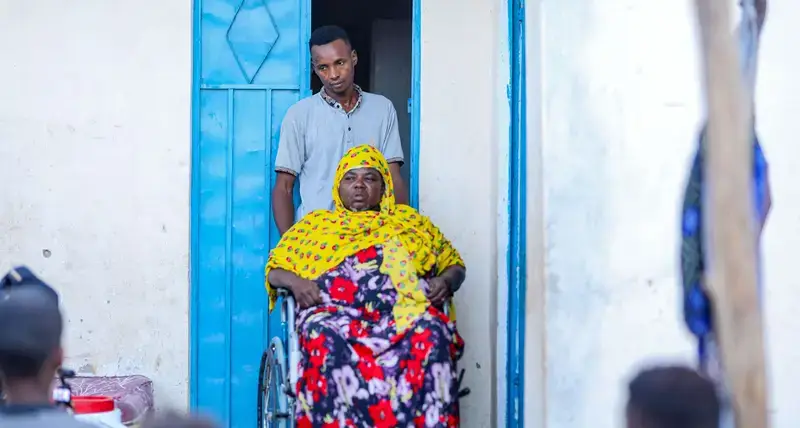 Mako Mohamud, whose newly acquired wheelchair has improved her mobility and independence, poses outside her permanent home in Gribble Settlement. © UN-Habitat