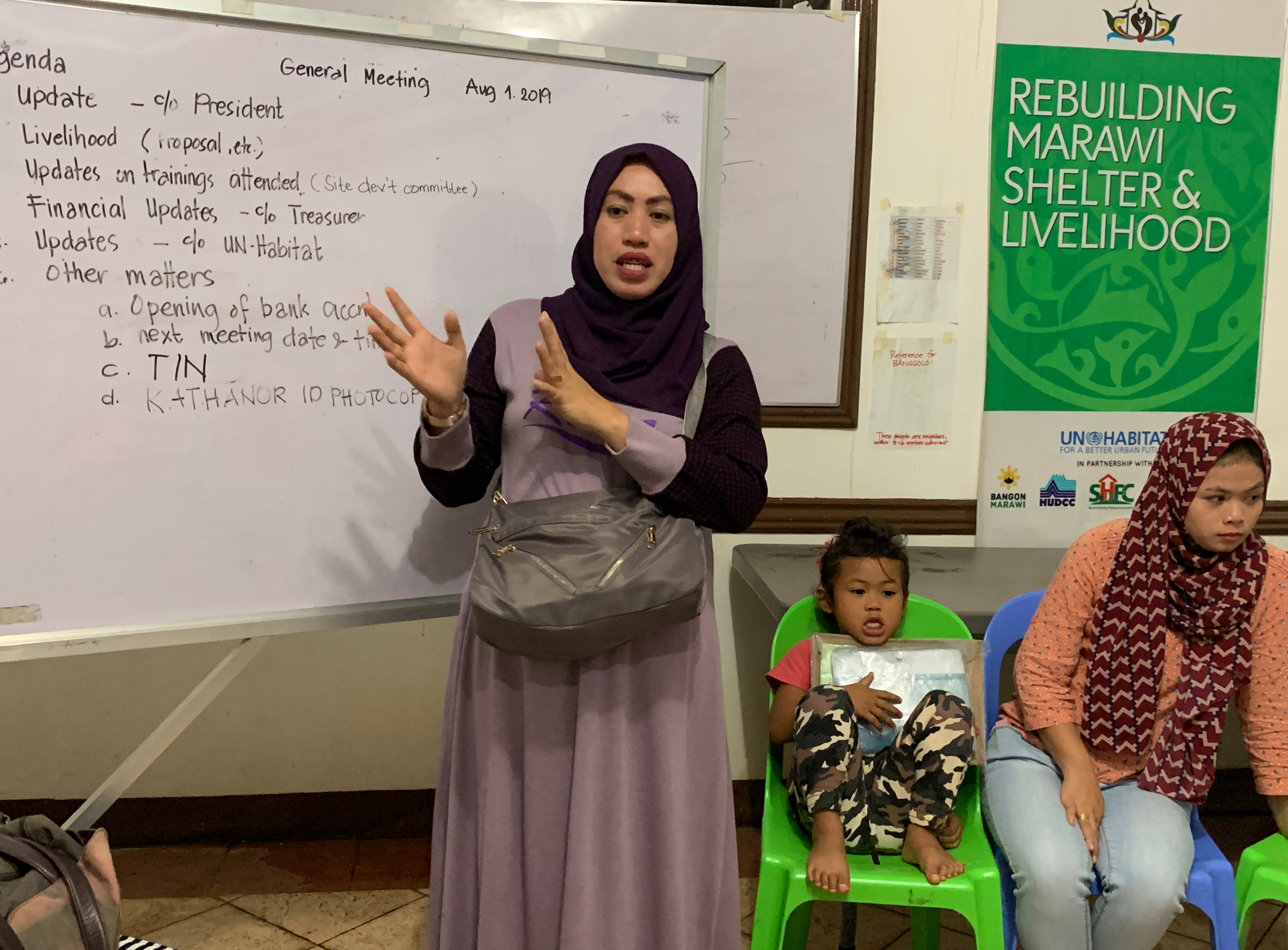 Woman talking in a classroom in front of whiteboard.