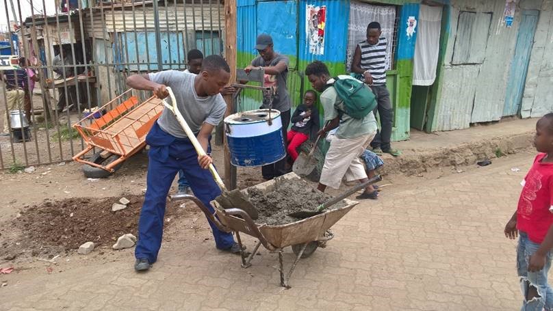 University students collaborating with local youth to install waste bins along the model street