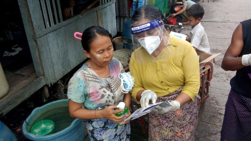 UN-Habitat community volunteer assists a slum resident in Yangon, Myanmar to fit a COVID-19 mask properly as part of community outreach providing accurate information on the pandemic