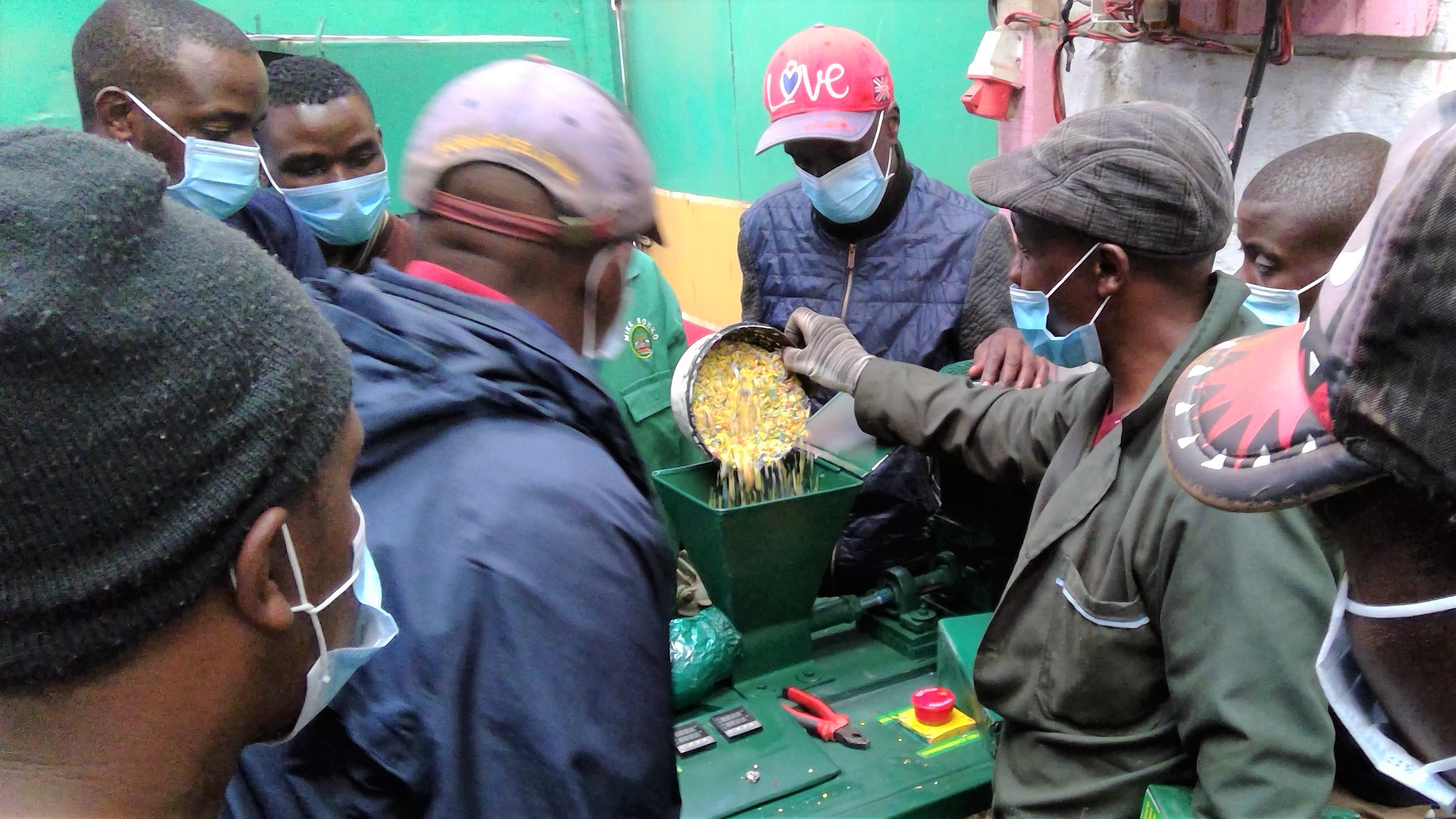 Young people in Nairobi’s informal settlement of Mathare are trained by UN-Habitat on using a new plastic recycling machine to generate livelihoods lost as a result of COVID-19 in November 2020 