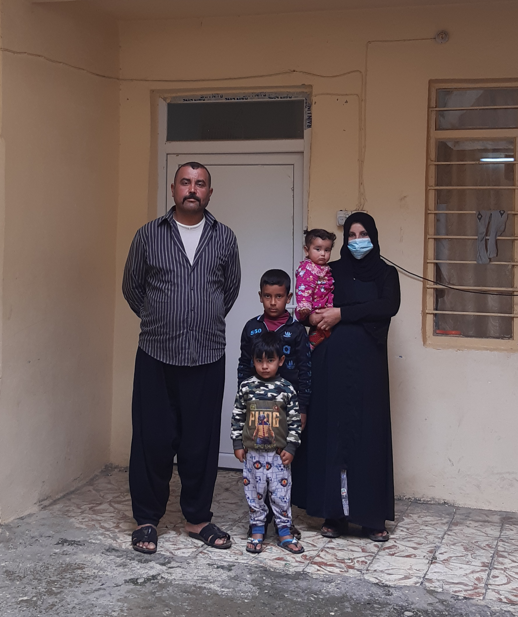 Ismail Faris and Um Medyan stand with their children outside their rehabilitated house in the Al-Shifaa neighbourhood of Mosul, Iraq.