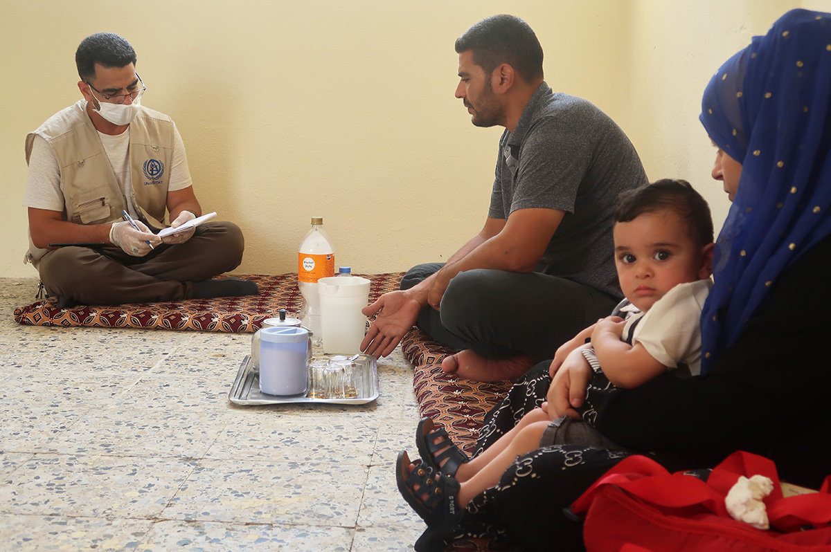 Omar and his family inside their newly rehabilitated house talk with UN-Habitat field engineer, Fathy Mohammed, on their appreciation of UN-Habitat’s work