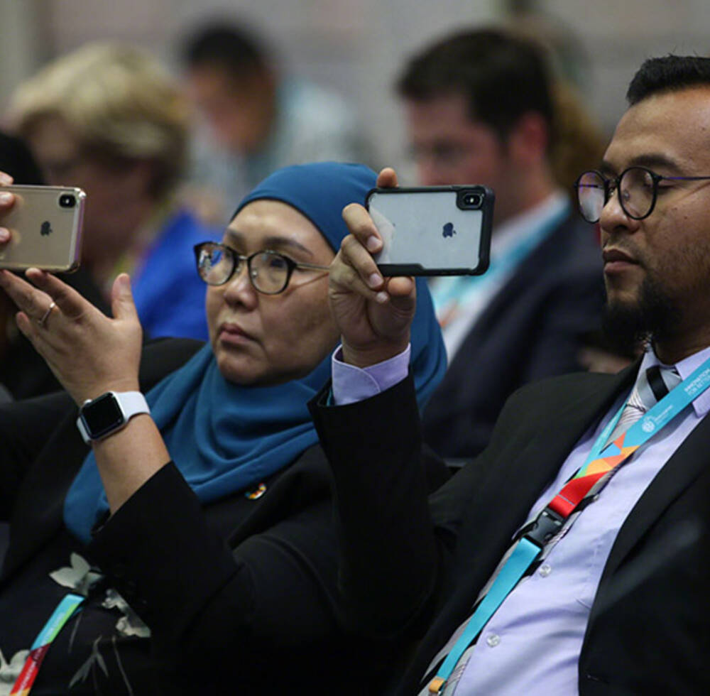 Delegates in plenary film with their phones while hearing the national statements