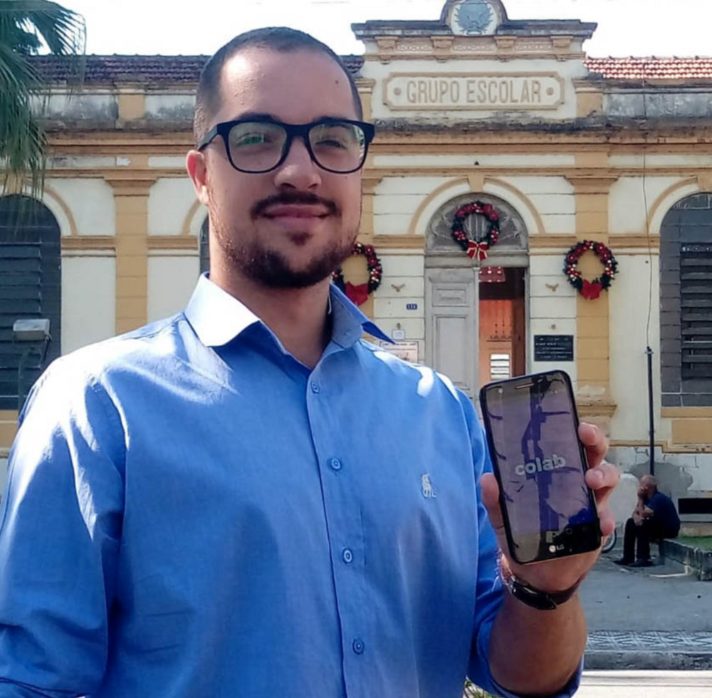  A young man in Brazil holds a mobile phone with the app that holds cities accountable.