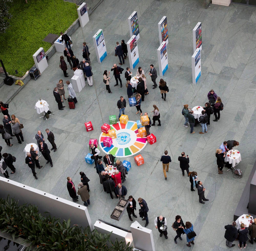 People in an event, gathering around boxes of the Sustainable Development Goals