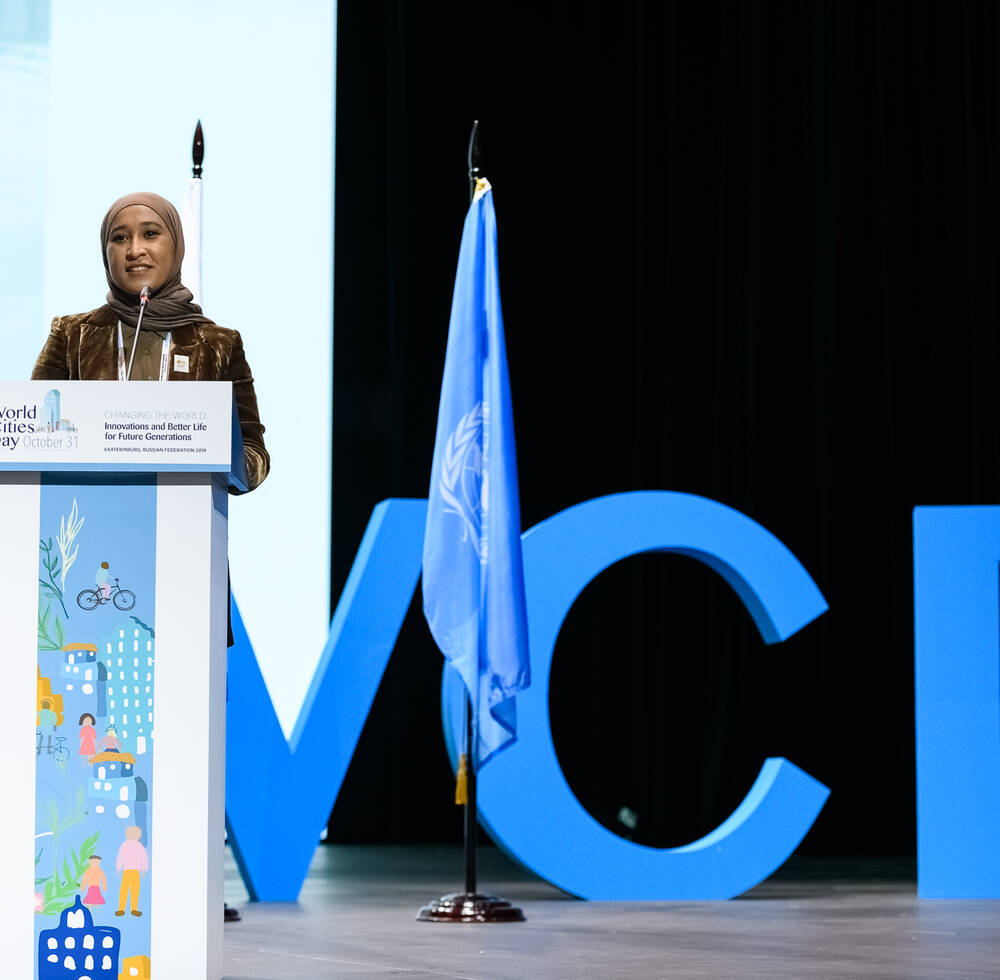 A presentation in front of the UN flag and the World Cities Day letters.