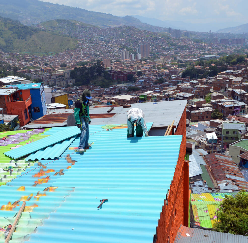Local artist replace the old iron sheets with the new once in Medellin, Colombia