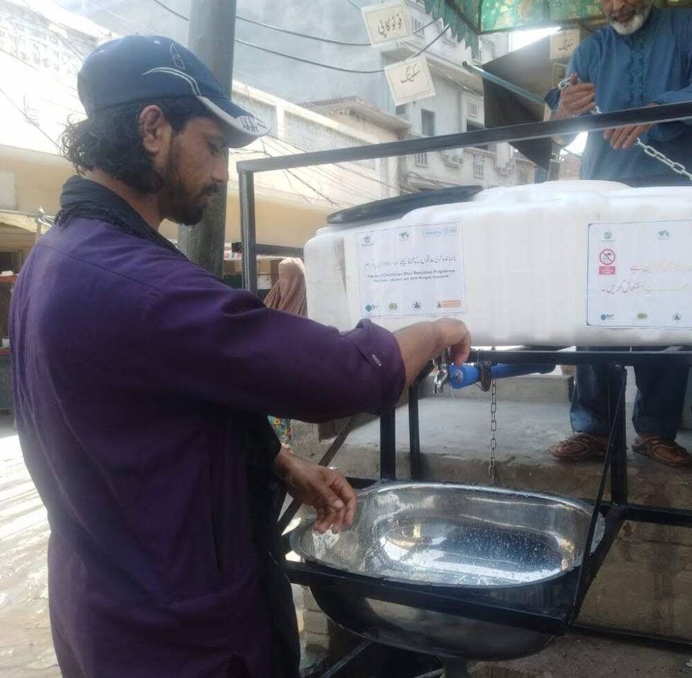 A shopkeeper washes his hands at facility provided by UN-Habitat as part of efforts to stop the spread of COVID-19 in the Pakistani city of Rawalpindi.