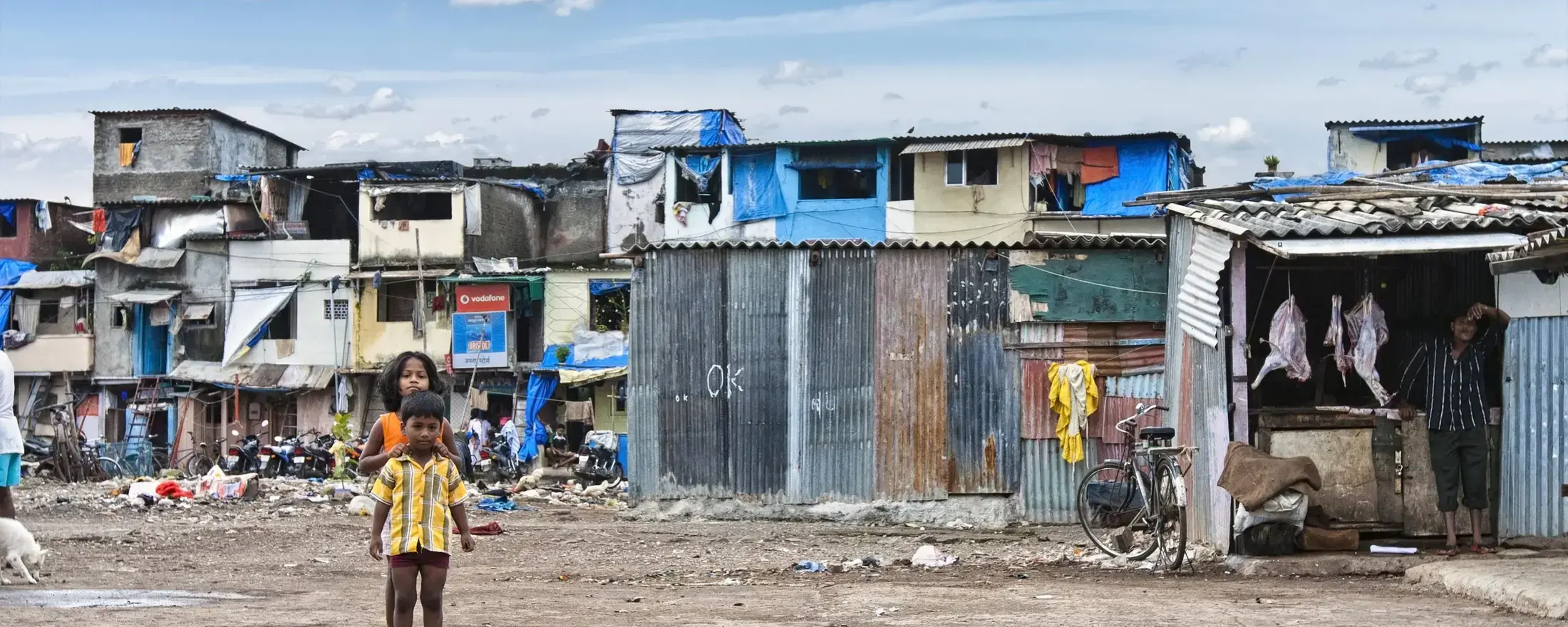 Two children standing in front of slum houses.