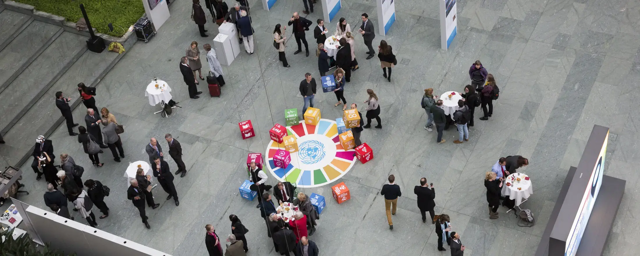 People in an event, gathering around boxes of the Sustainable Development Goals