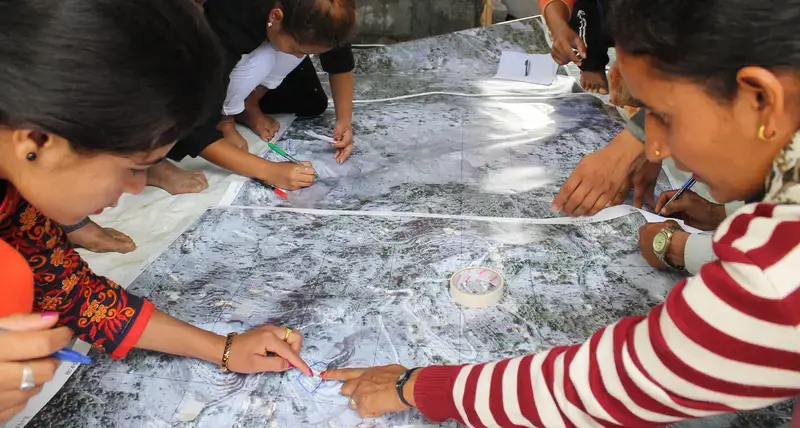 Four Nepalese residents point to a map while discussing sanitation issues.