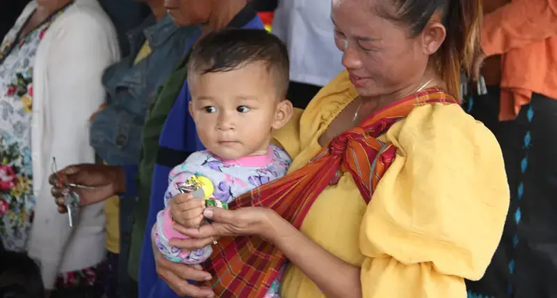 child holds a symbolic house key as the newly constructed houses were handed over to the people
